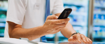 Mitarbeitender im weissen Hemd hält Smartphone Mitarbeitender im weissen Hemd hält Smartphone